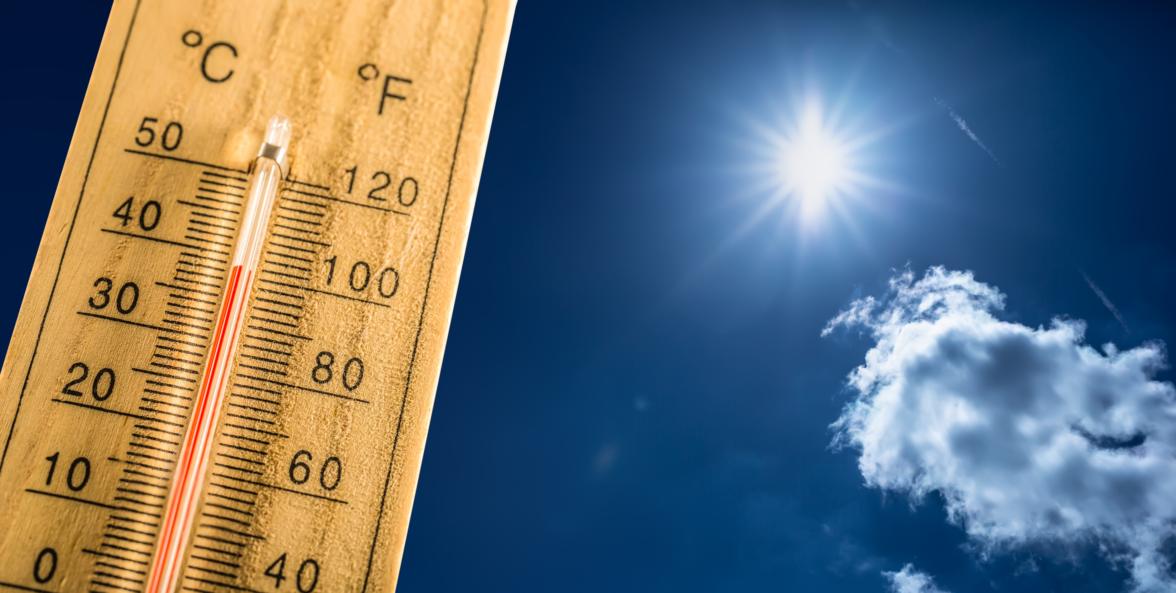 Wooden thermometer in sunlight showing high temperature, concept for heatwave or hot weather