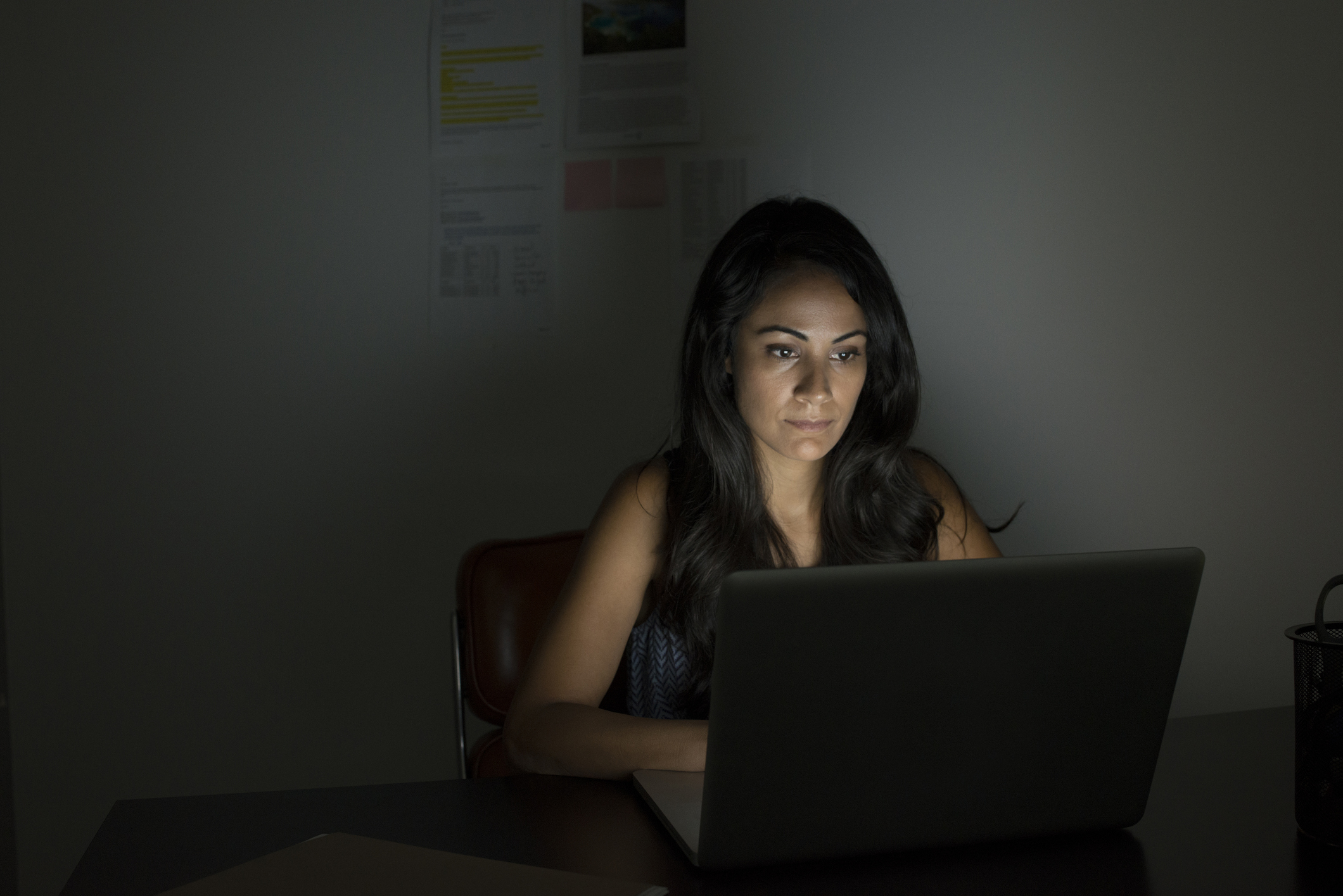 Woman working on a laptop in a dimly lit room