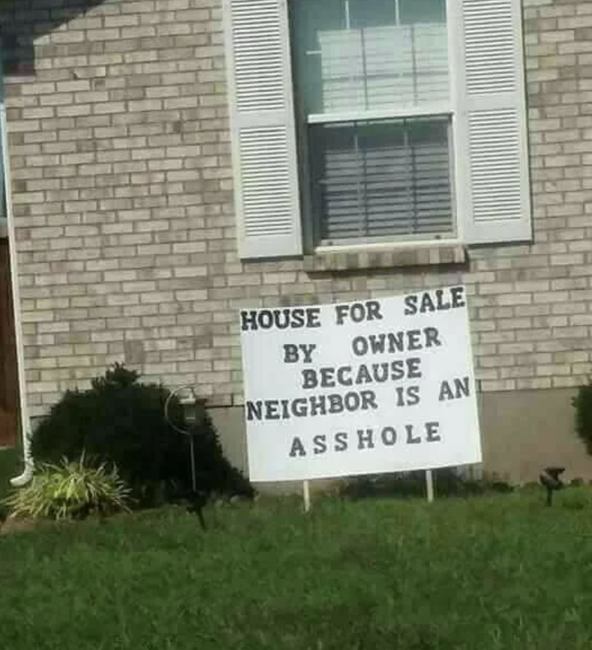 Handwritten sign in front of a house stating it&#x27;s for sale by owner due to an unpleasant neighbor