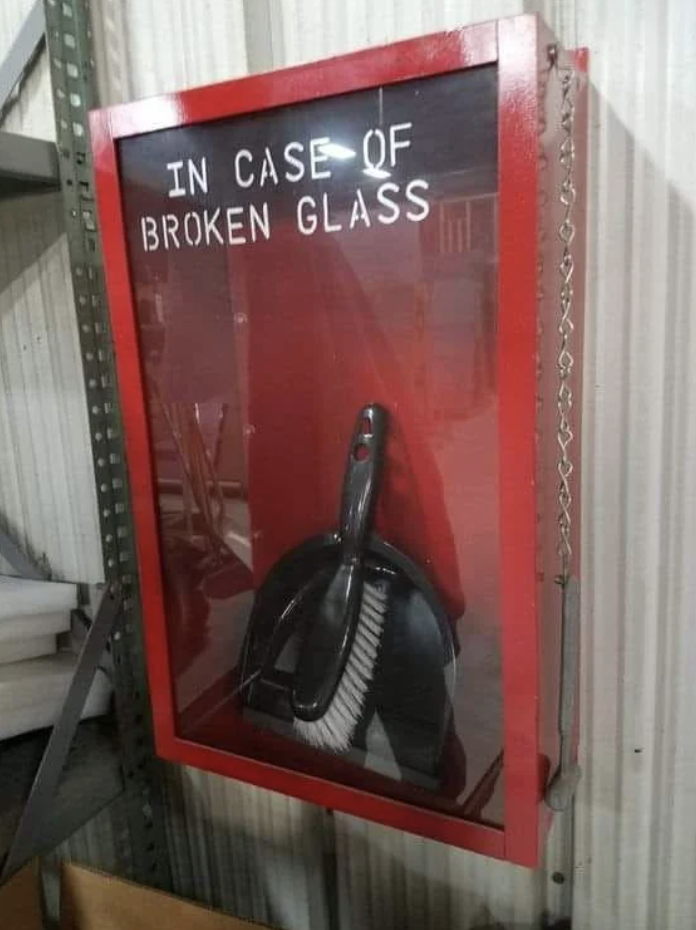 Sign reads &quot;IN CASE OF BROKEN GLASS&quot; with a dustpan and brush inside a red box