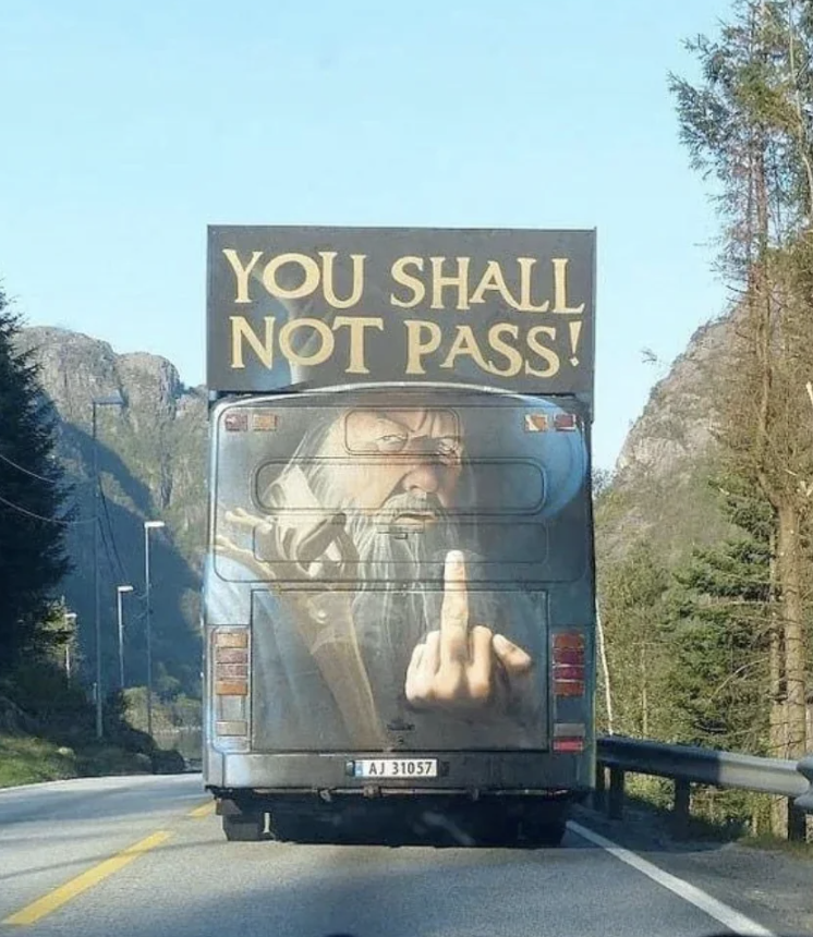 Rear of a bus with a graphic of Gandalf and text &quot;YOU SHALL NOT PASS!&quot; blocking a road
