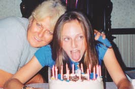 Woman leans in next to a younger female blowing out candles on a birthday cake. Both are smiling