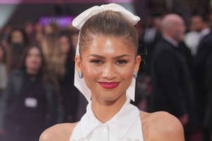 Zendaya in an elegant outfit with a bow head accessory, smiling at an event