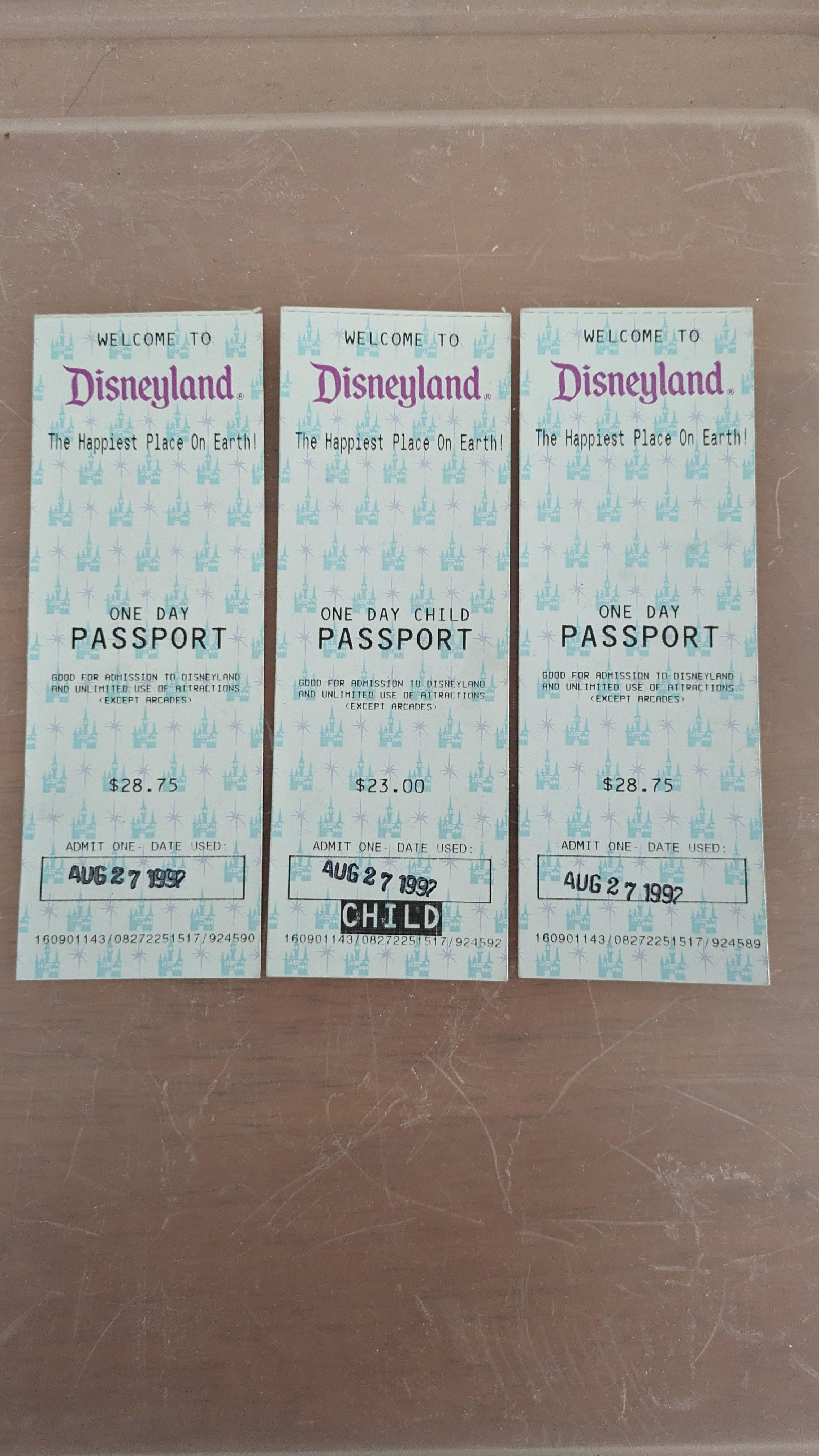 Three vintage Disneyland passports displayed on a surface, dated August 27, 1989