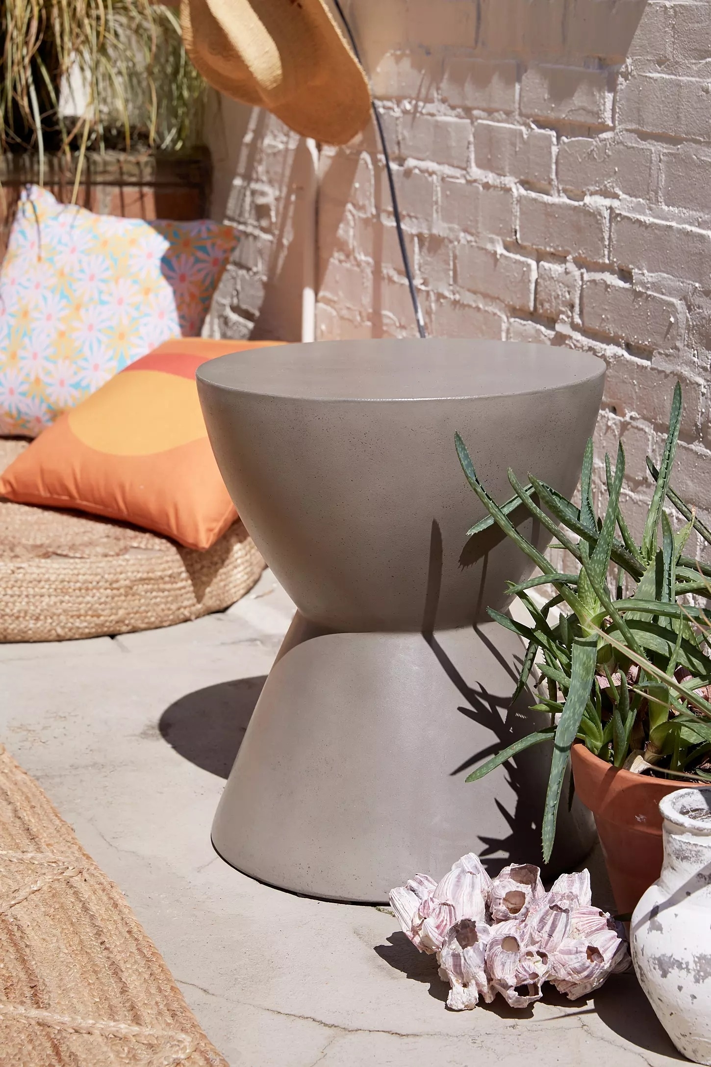Concrete side table in an outdoor setting with plant and decorative items nearby
