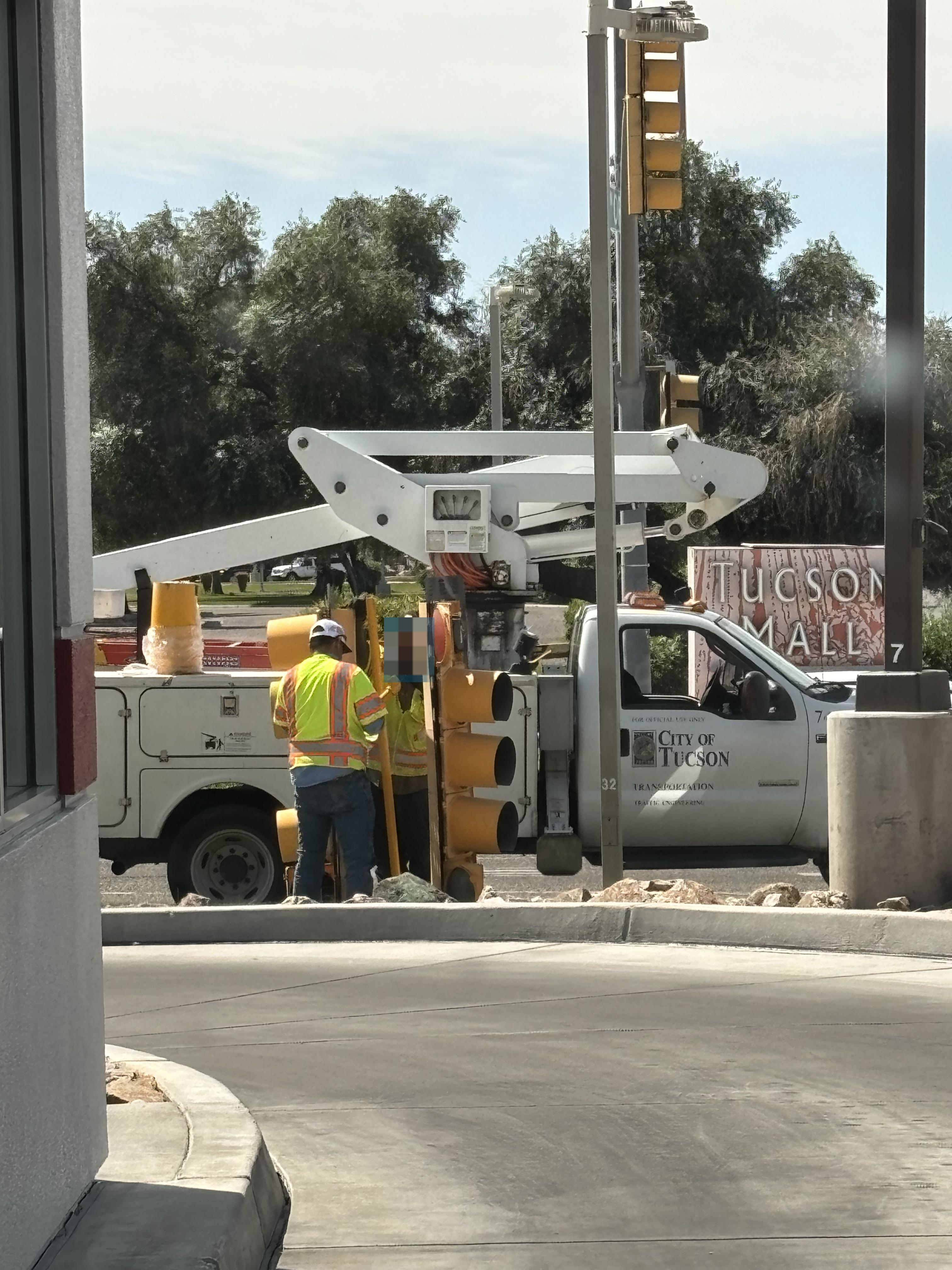 Two workers in safety vests operating a cherry picker near a &quot;City of Tucson&quot; truck