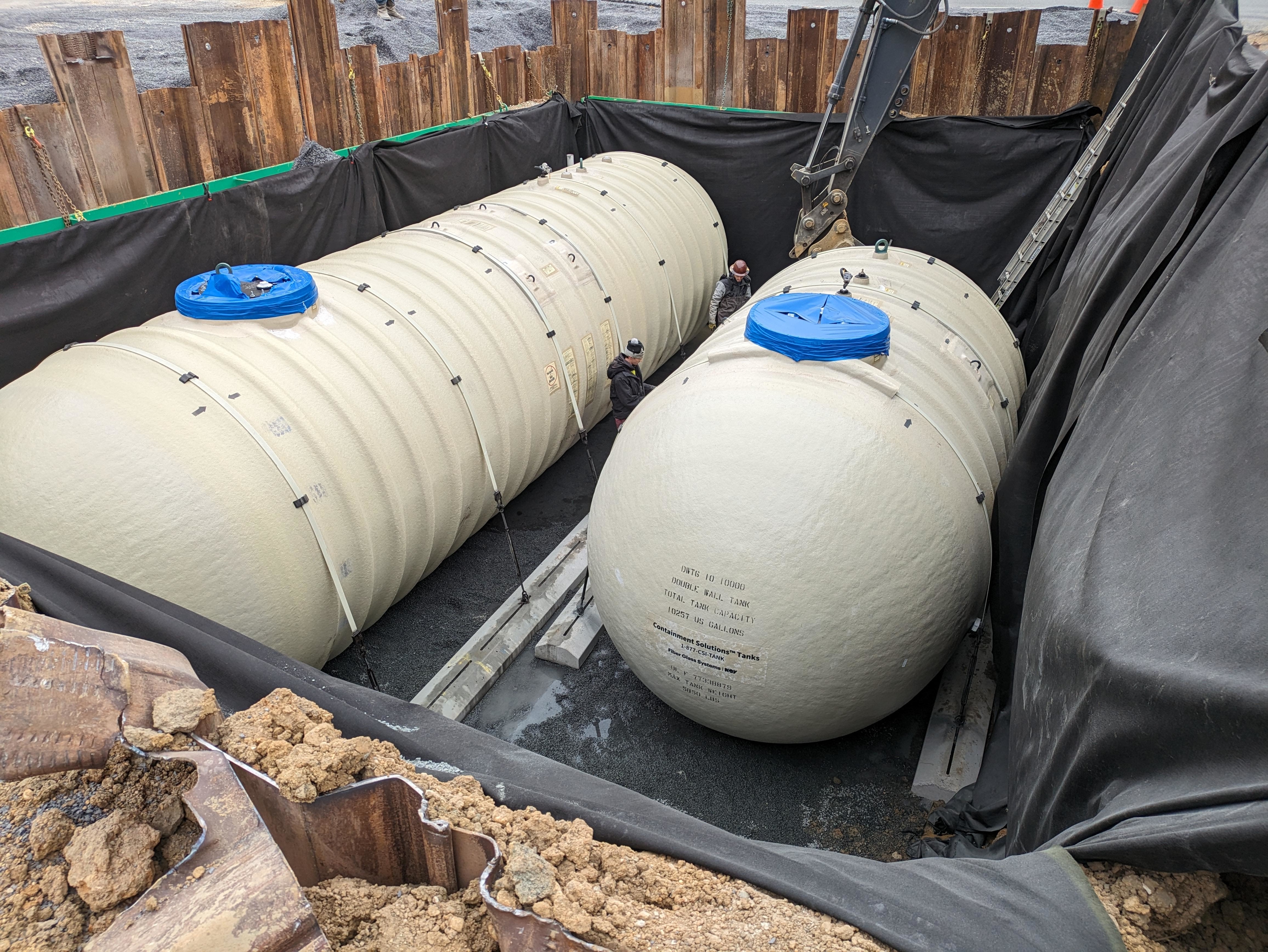 Two large, cylindrical tanks installed underground with visible pipes and protective covering