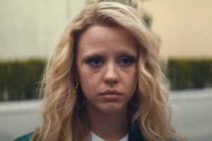 Image of actress with curly hair and a high school jacket, portraying a troubled expression. (Character name cannot be provided)