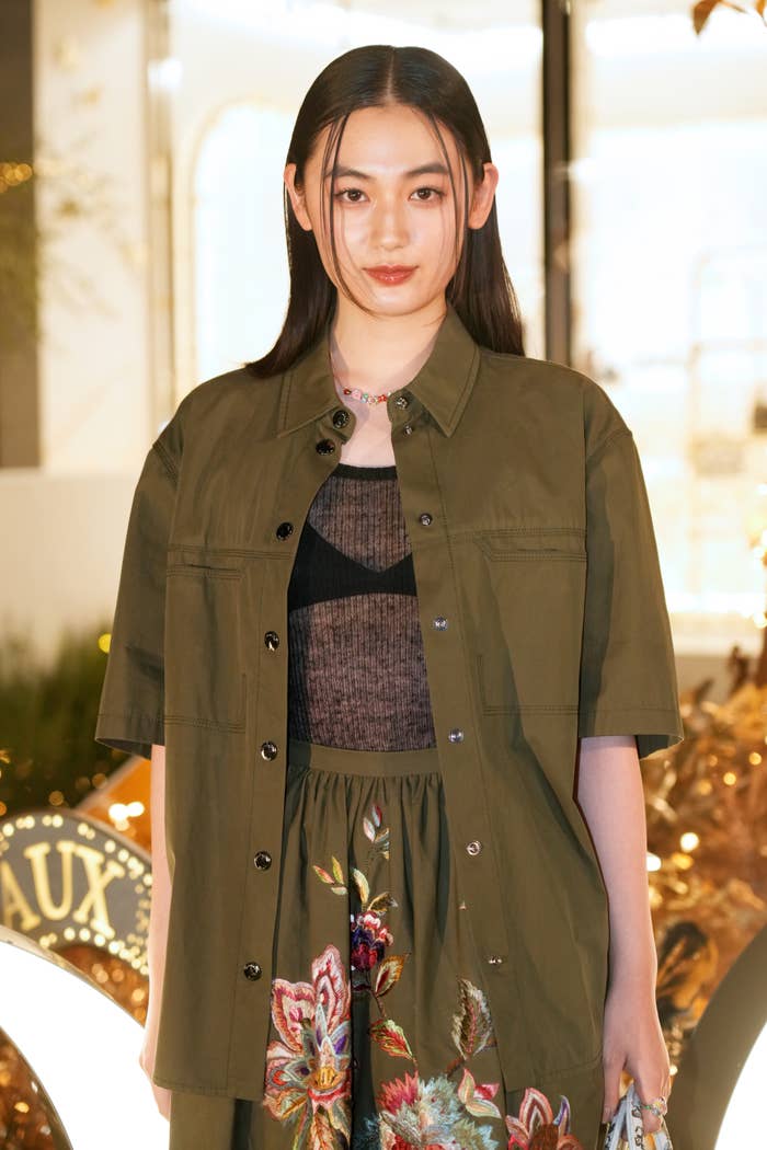 八木莉可子さんが短めのカーキ色のジャケットと花柄のスカートを着用しています。