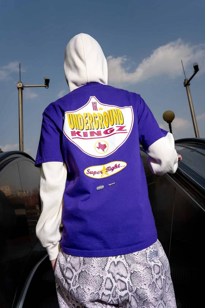 Person in a hoodie and patterned pants standing by a car, back facing camera, with &quot;Dr. Underground King&quot; graphic on the hoodie
