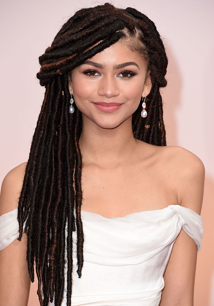 Zendaya smiles in an off-shoulder dress with her hair in locs