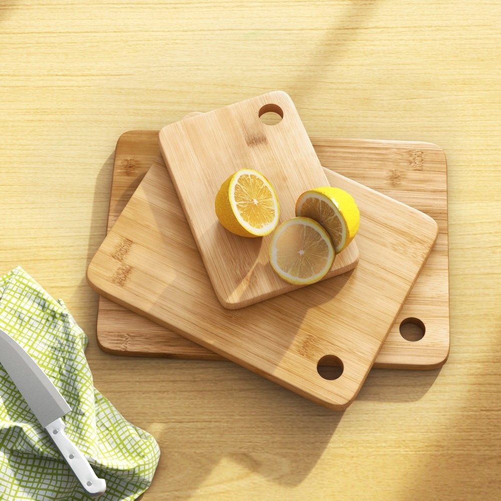 Three bamboo cutting boards on a table with sliced lemon, a knife, and a checkered cloth