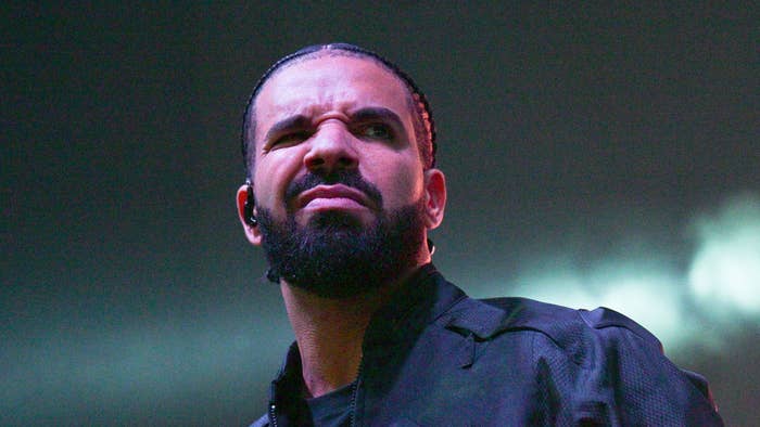 Drake in a black shirt performing on stage with a serious expression