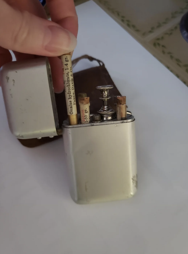 Person holding a small, vintage lighter with visible worn details
