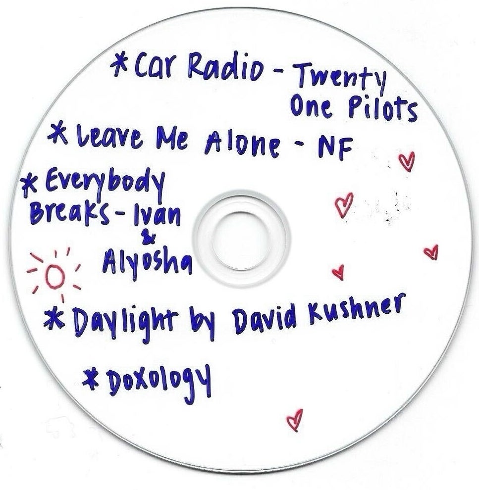 Handwritten song titles and artist names on a blank CD, including &quot;Car Radio&quot; and &quot;Daylight.&quot;