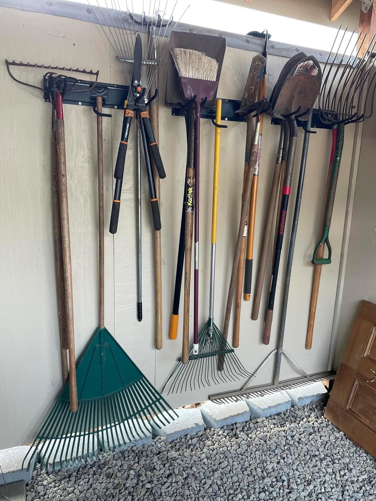 Assorted garden tools, including rakes and shovels, neatly hung on a wall for organization