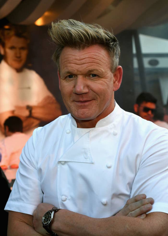 Gordon Ramsay in chef&#x27;s attire with crossed arms, standing in front of his portrait