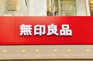 Sign with Chinese characters mounted on a red backdrop above a store entrance