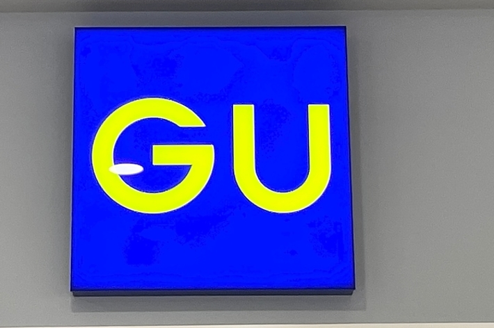 Sign with the letters &ldquo;GU&rdquo; mounted on a wall, indicating a brand or location