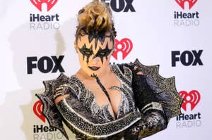 Person in bold makeup with a black and silver outfit poses at iHeart Radio event