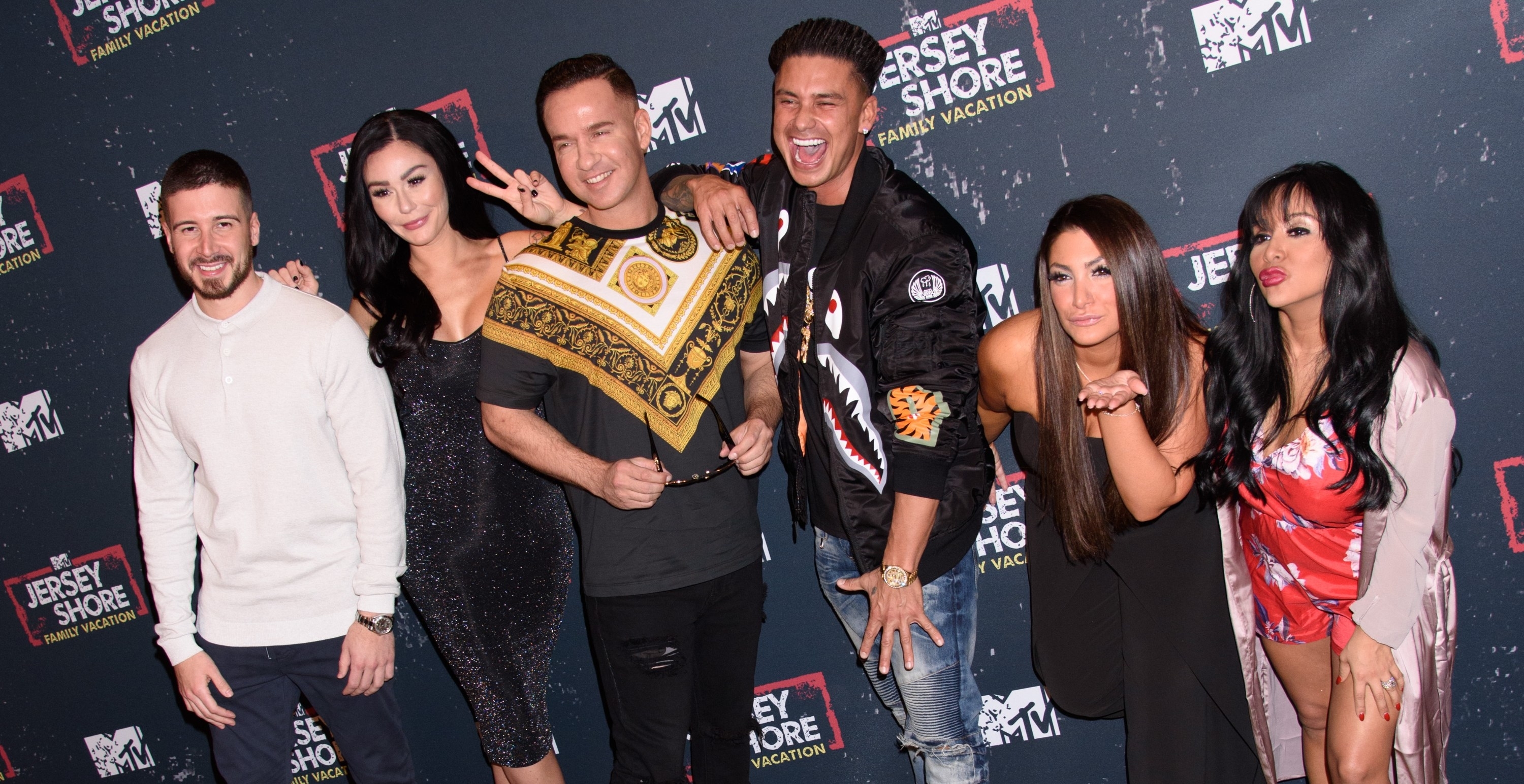 Cast of Jersey Shore posing together at event, with one holding a championship belt
