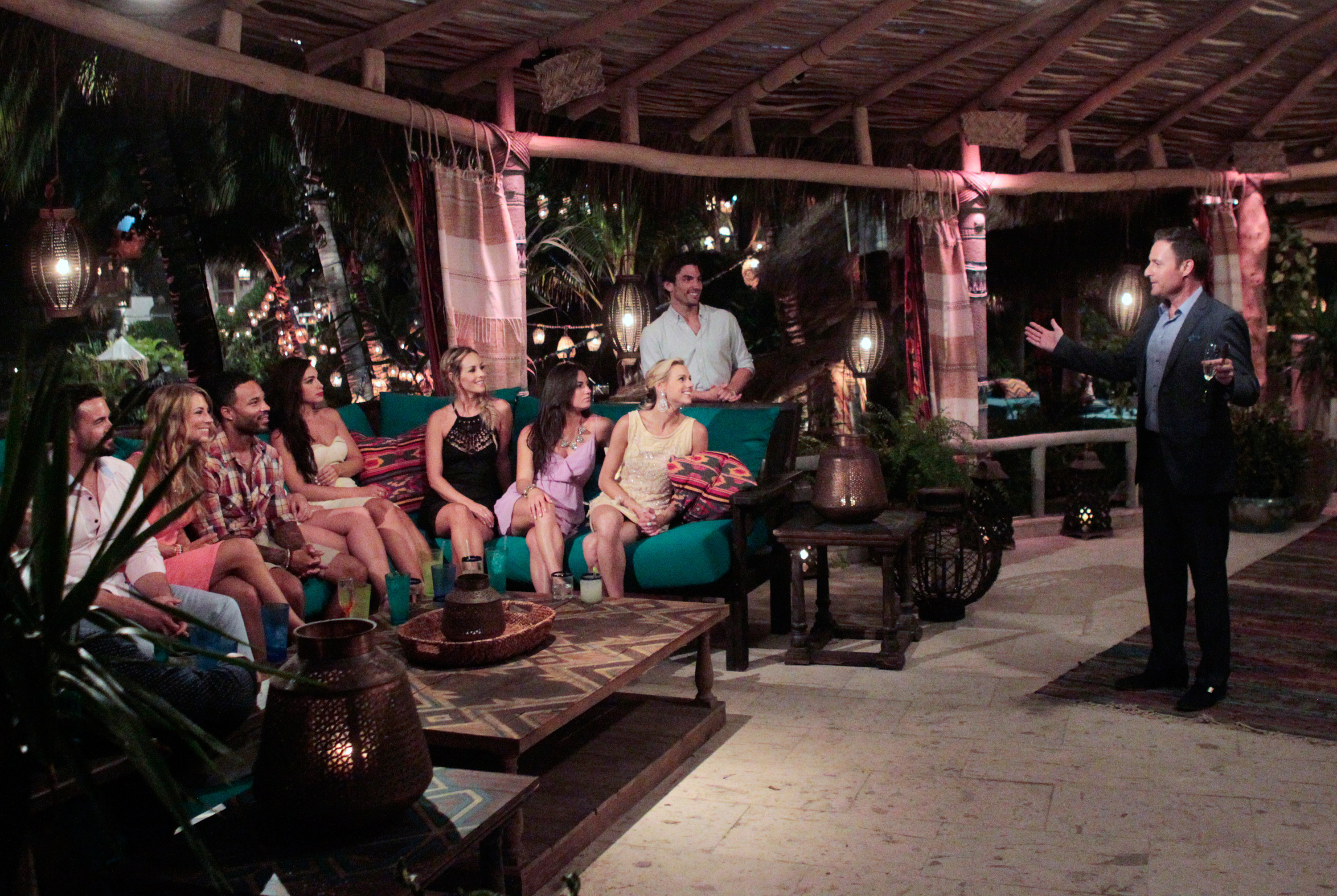 Group of people seated in a cozy outdoor lounge setting with a standing man addressing them