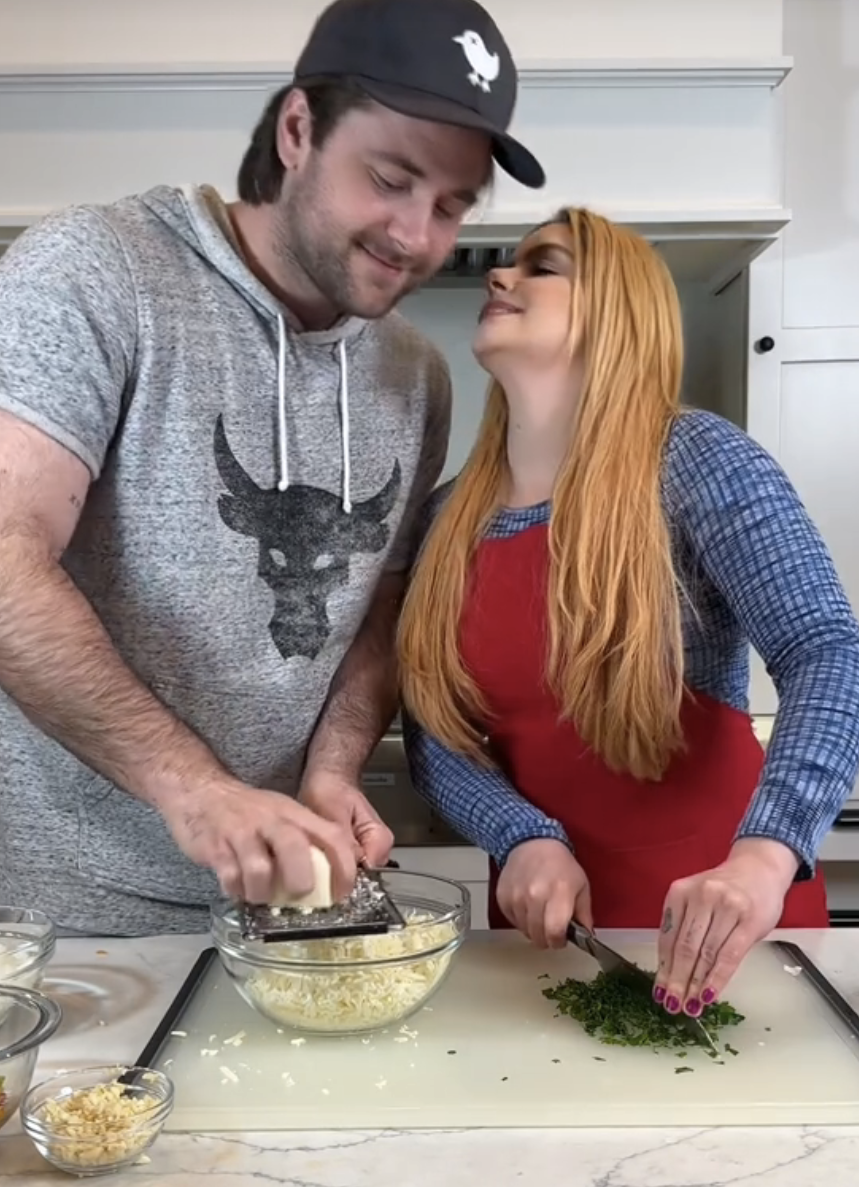Two people wearing casual clothes cooking together in a kitchen setting