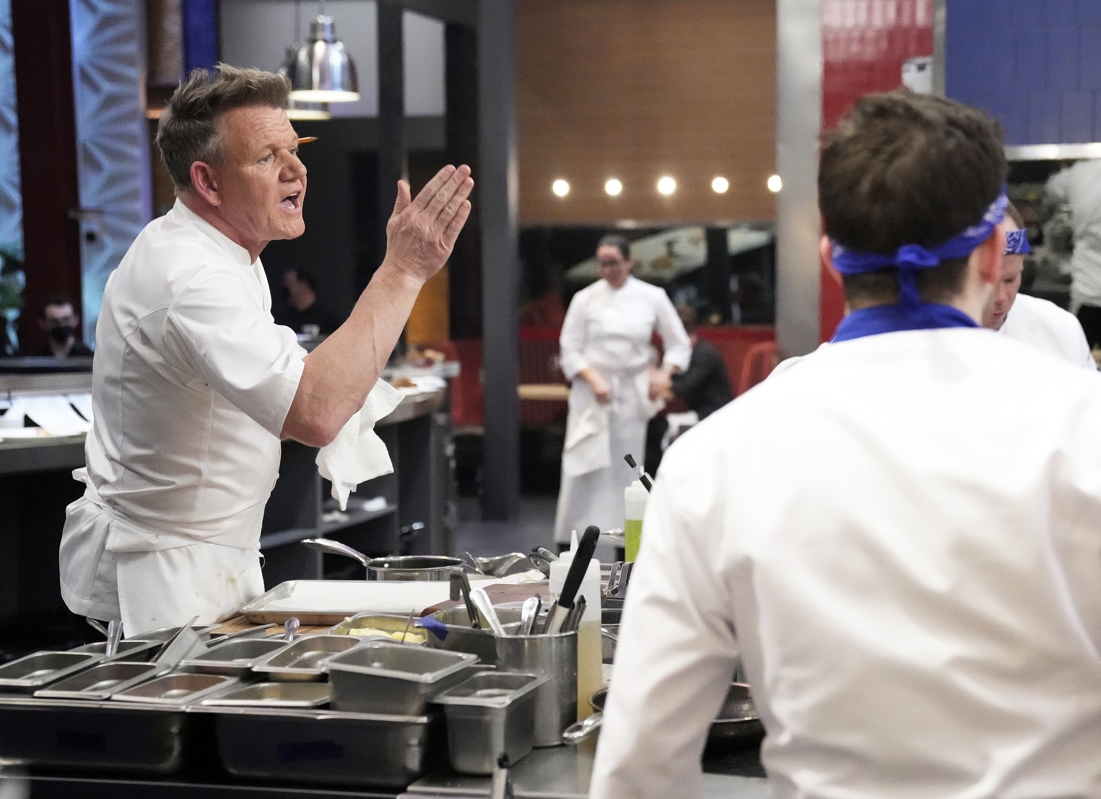 Gordon Ramsay gesturing and speaking to a chef in a kitchen during a cooking competition