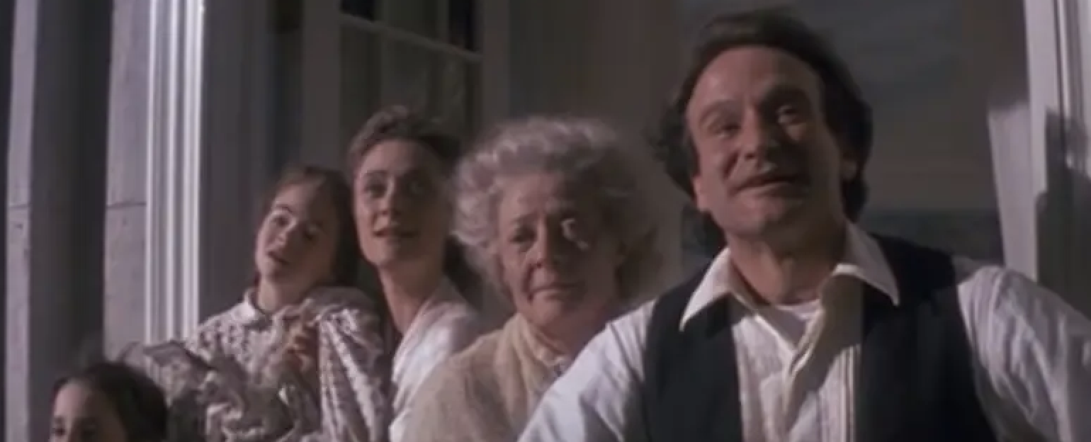 A group of actors portraying a family smiling and looking out from a porch in a scene from a film
