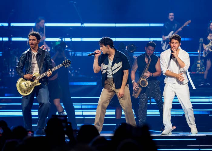 Jonas Brothers performing onstage with instruments and microphones
