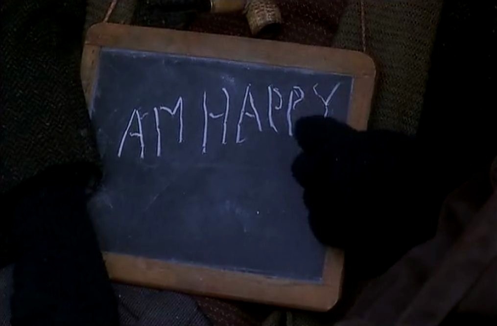 Chalkboard with the question &quot;Am I happy?&quot; written on it, held by a person in gloves
