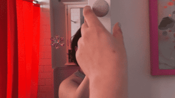 Person reaching for a peephole on a door, with another person visible in the background