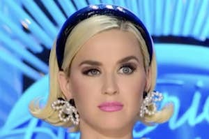 Katy Perry with a headband, wearing pearl earrings, on a TV show set