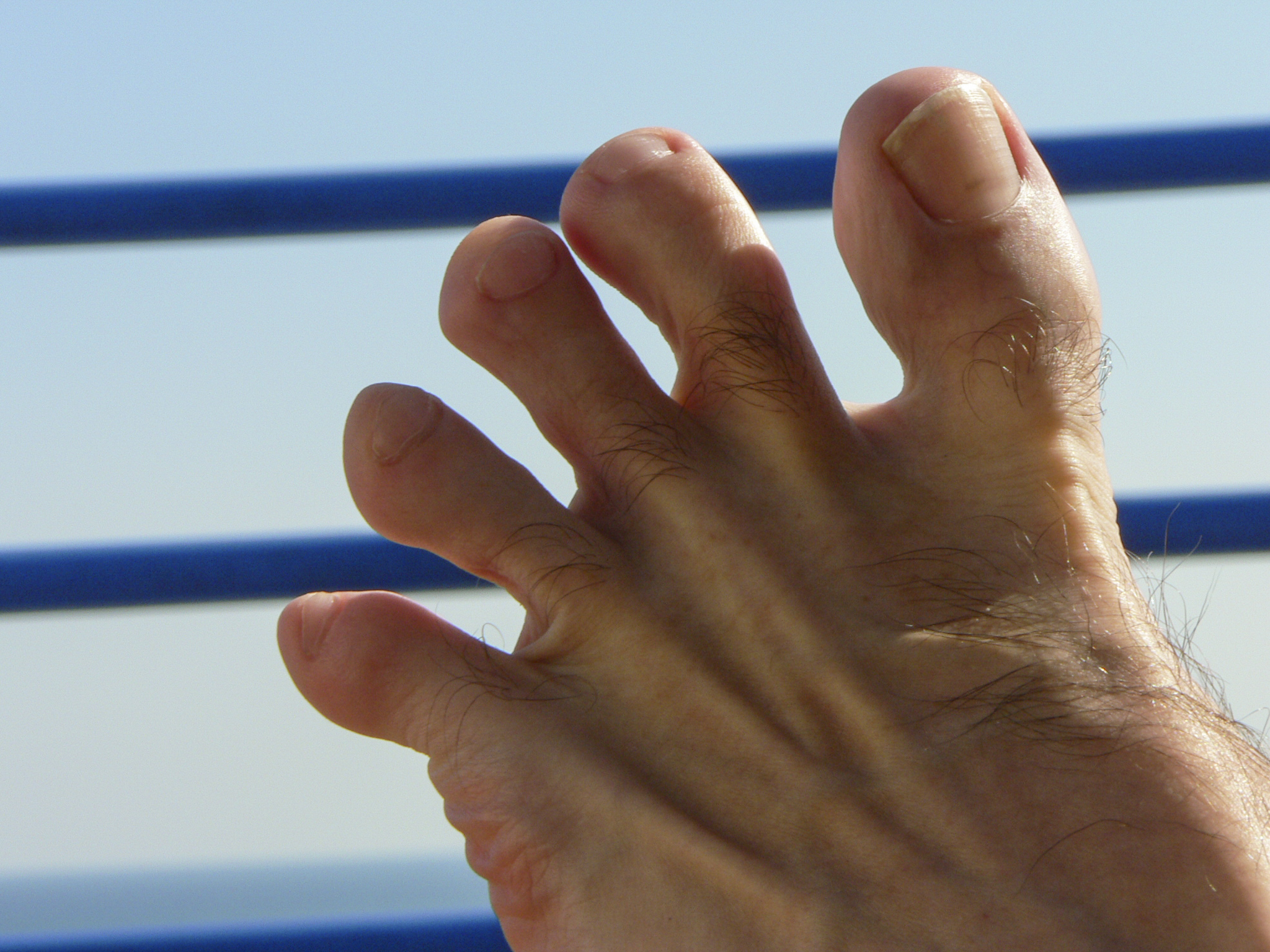 Close-up of a person&#x27;s bare foot with toes spread out against a blue background