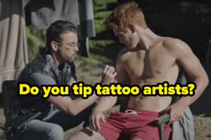 Man applying makeup to another shirtless man on a film set, with motorcycle in background