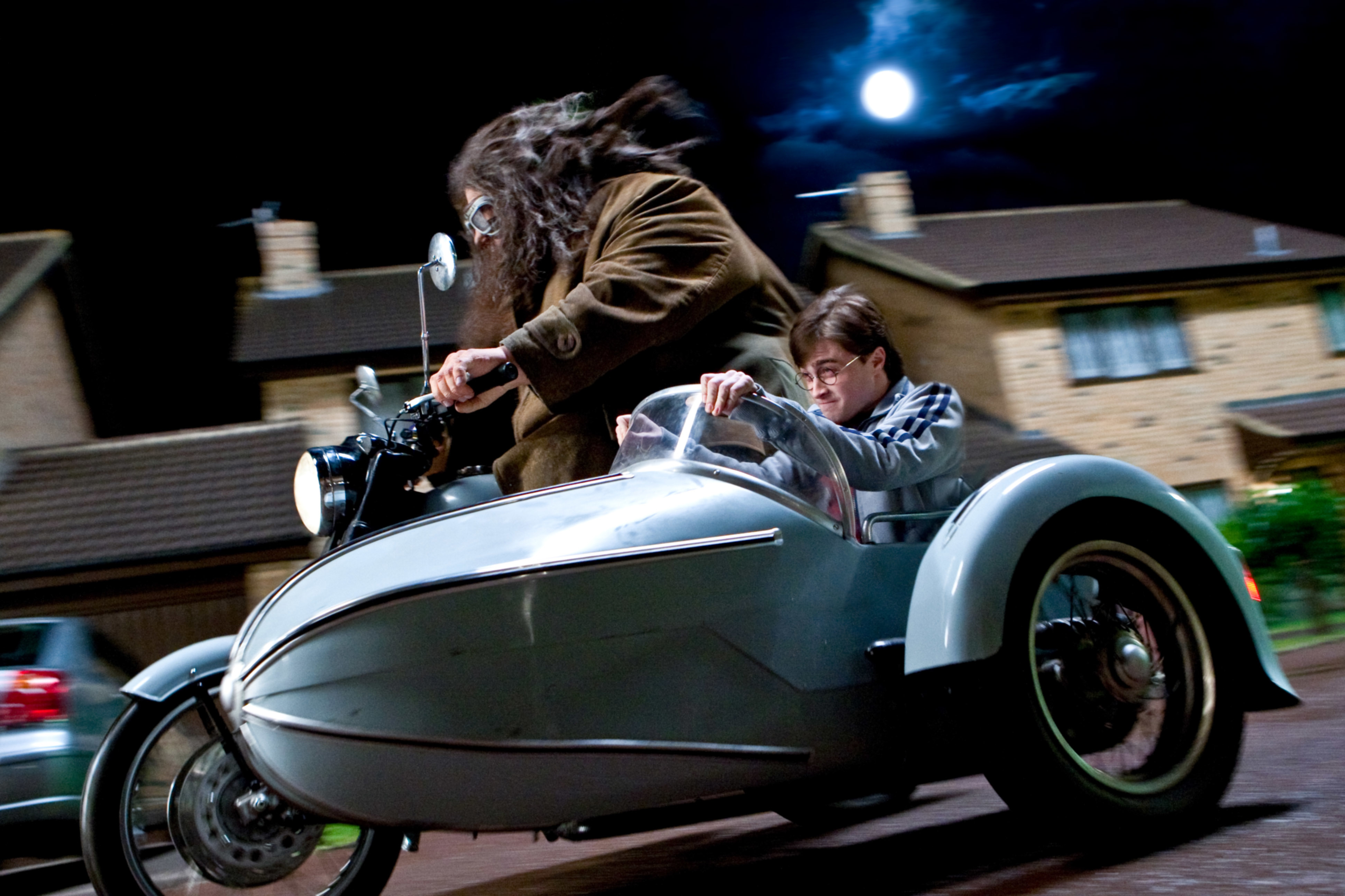 Hagrid and Harry Potter riding a motorcycle with a sidecar at night