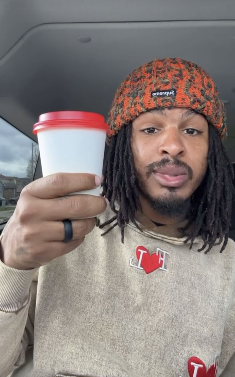 Keith in beanie holding a coffee cup with car interior background