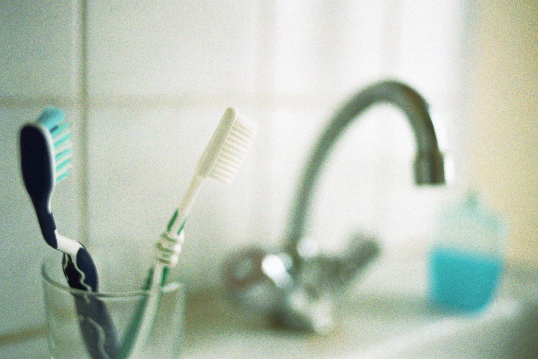 Two toothbrushes in a cup near a bathroom sink, symbolizing cohabitation and shared routines
