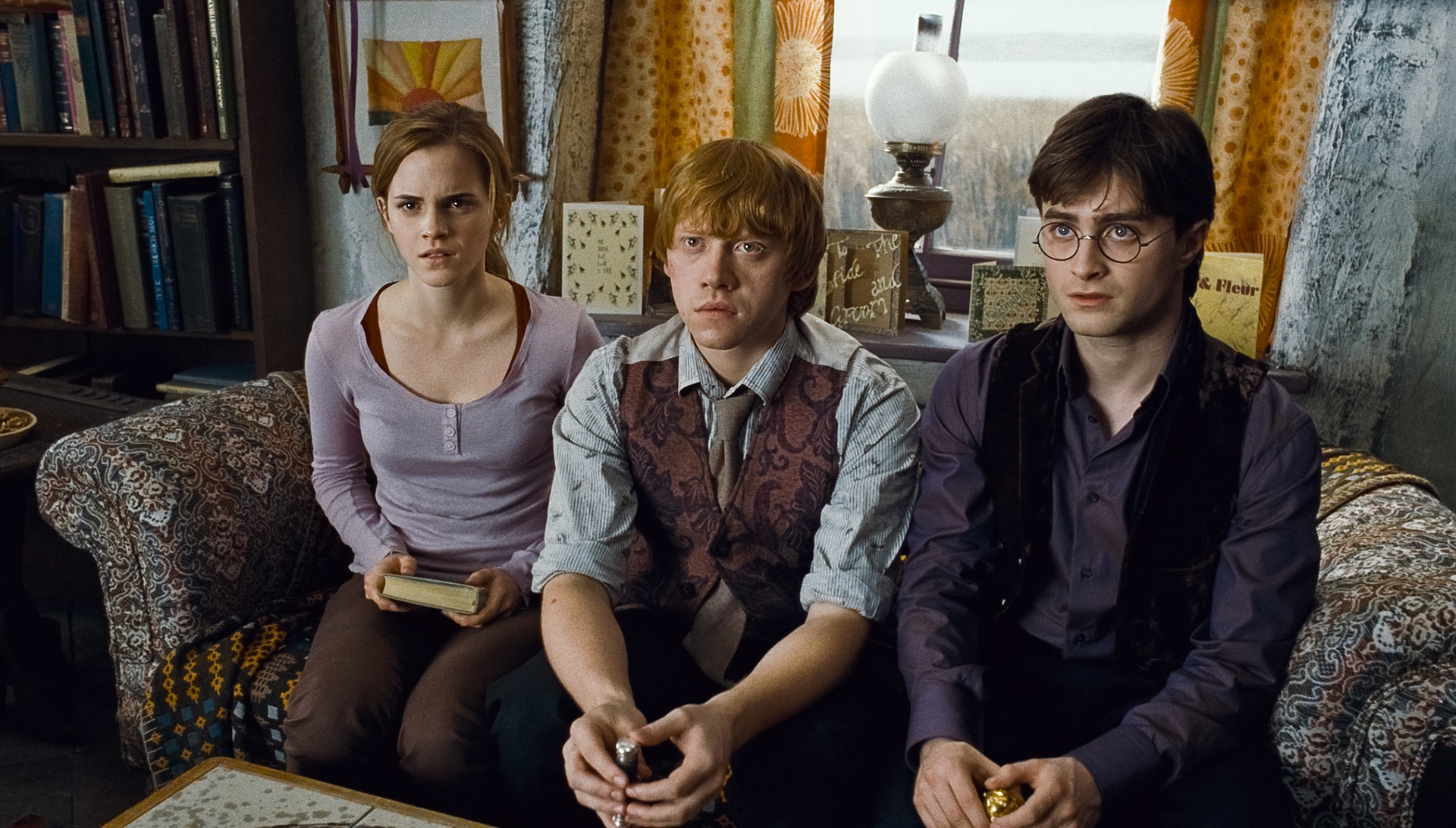 Hermione Granger, Ron Weasley, and Harry Potter sitting together with serious expressions