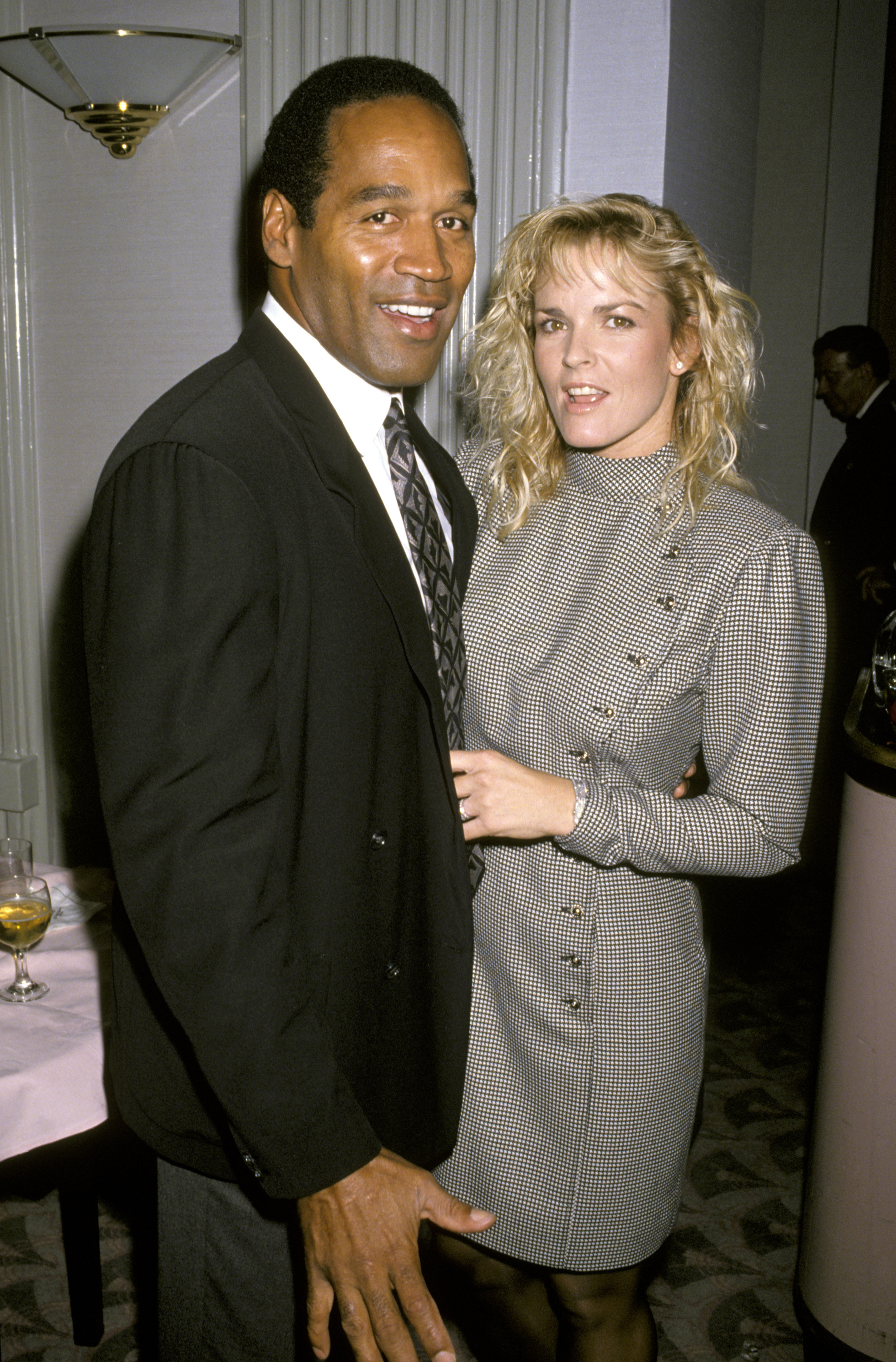 O.J. Simpson and Nicole Brown Simpson posing together, Nicole in a patterned dress with buttons, O.J. in a suit with striped tie