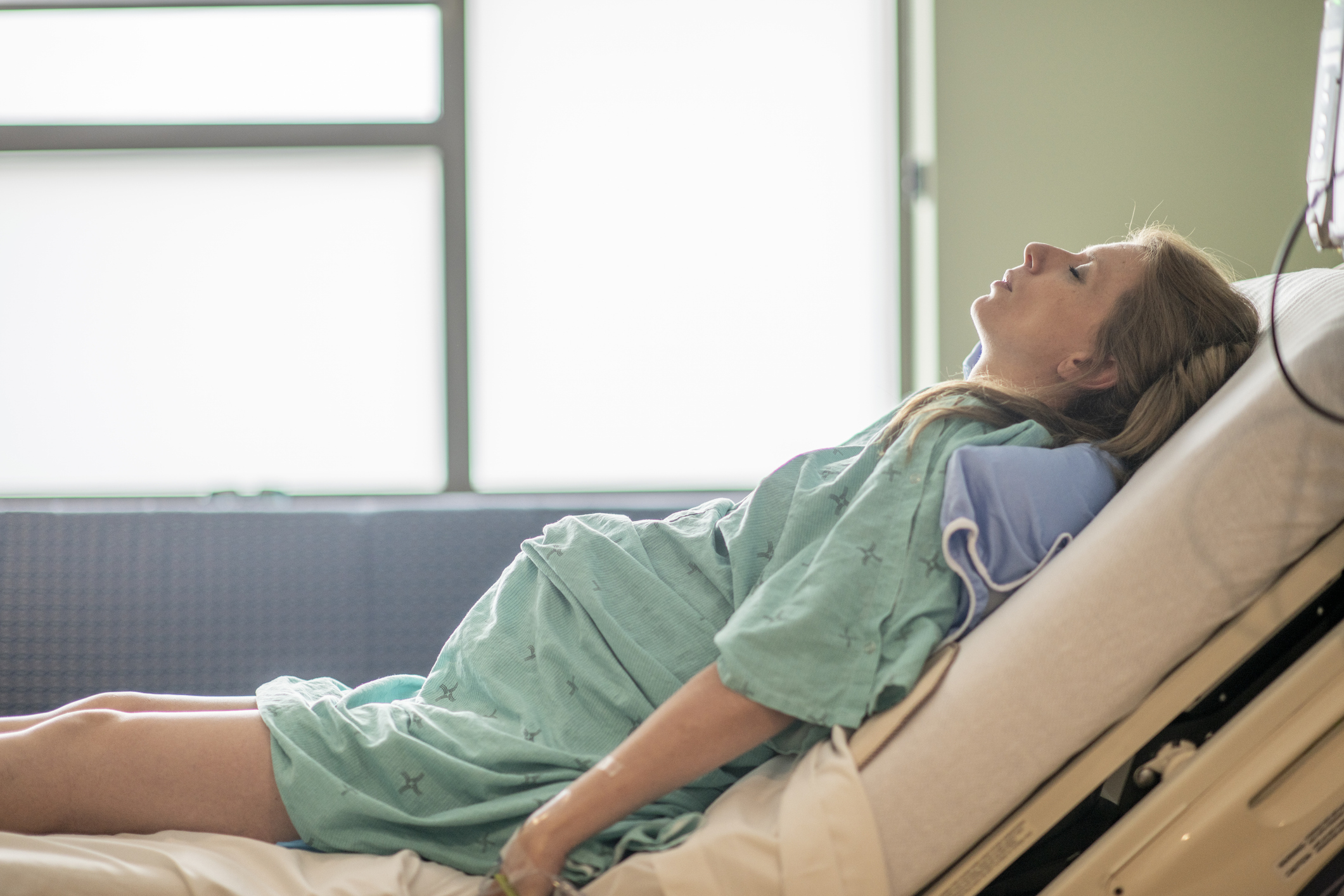 Expectant parent resting on a hospital bed, looking thoughtful