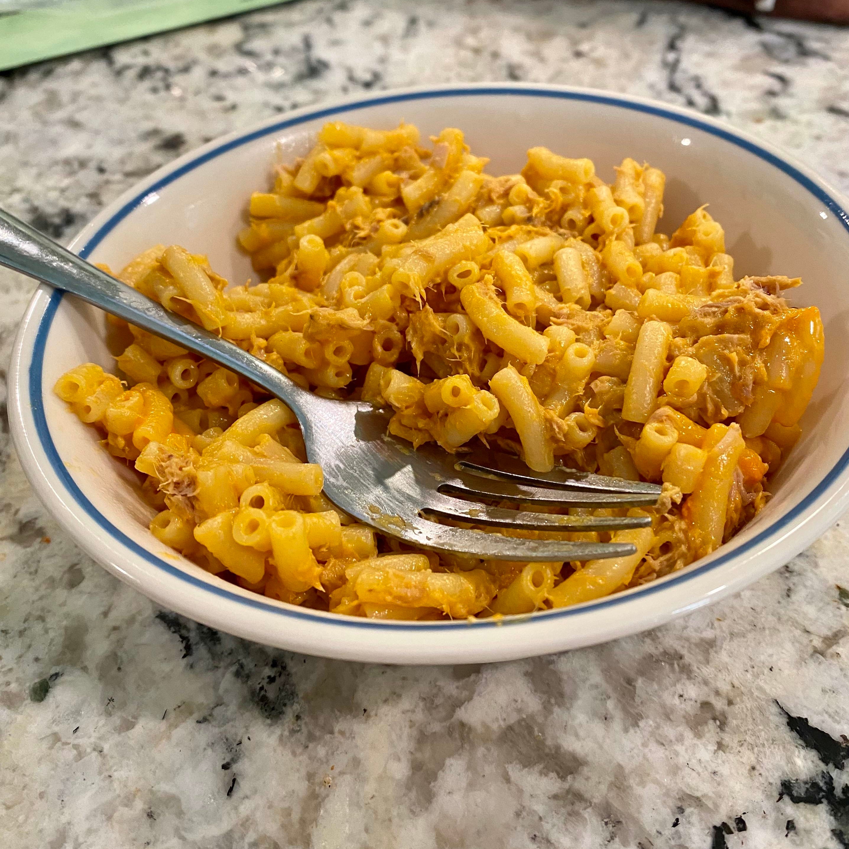 Bowl of macaroni and cheese with a fork on a kitchen counter