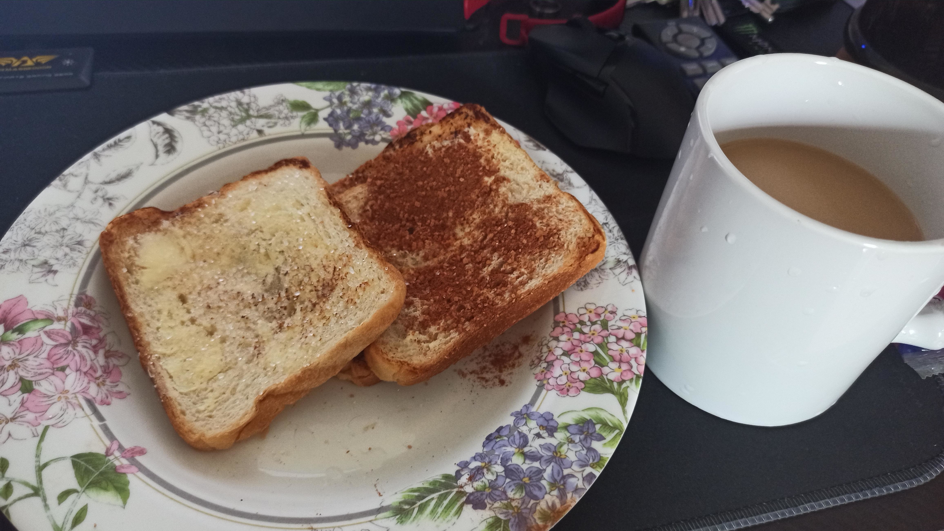 A plate with two slices of buttered toast next to a mug of coffee