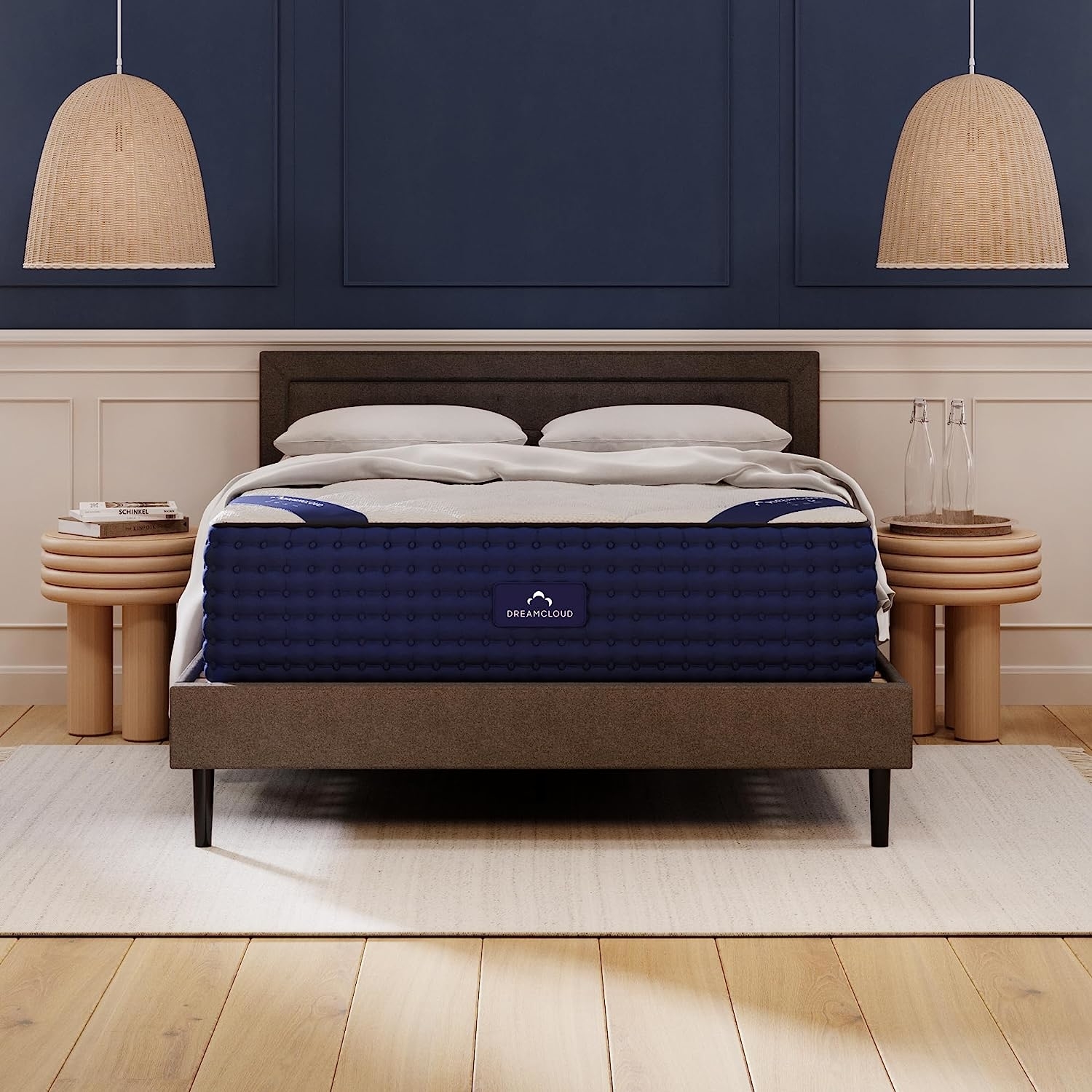 A DreamCloud mattress on a bed frame in a bedroom setting, flanked by bedside tables and lamps