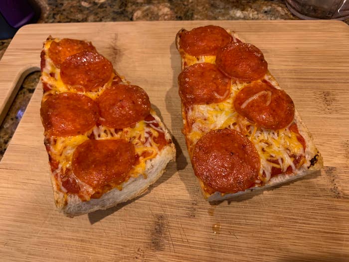 Two slices of pepperoni pizza on a wooden cutting board