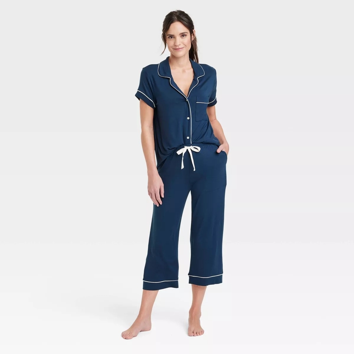 Model in a navy pajama set with white trim and a drawstring waist