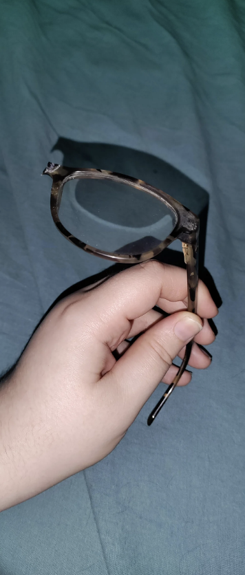 Hand holding a pair of glasses with one lens missing