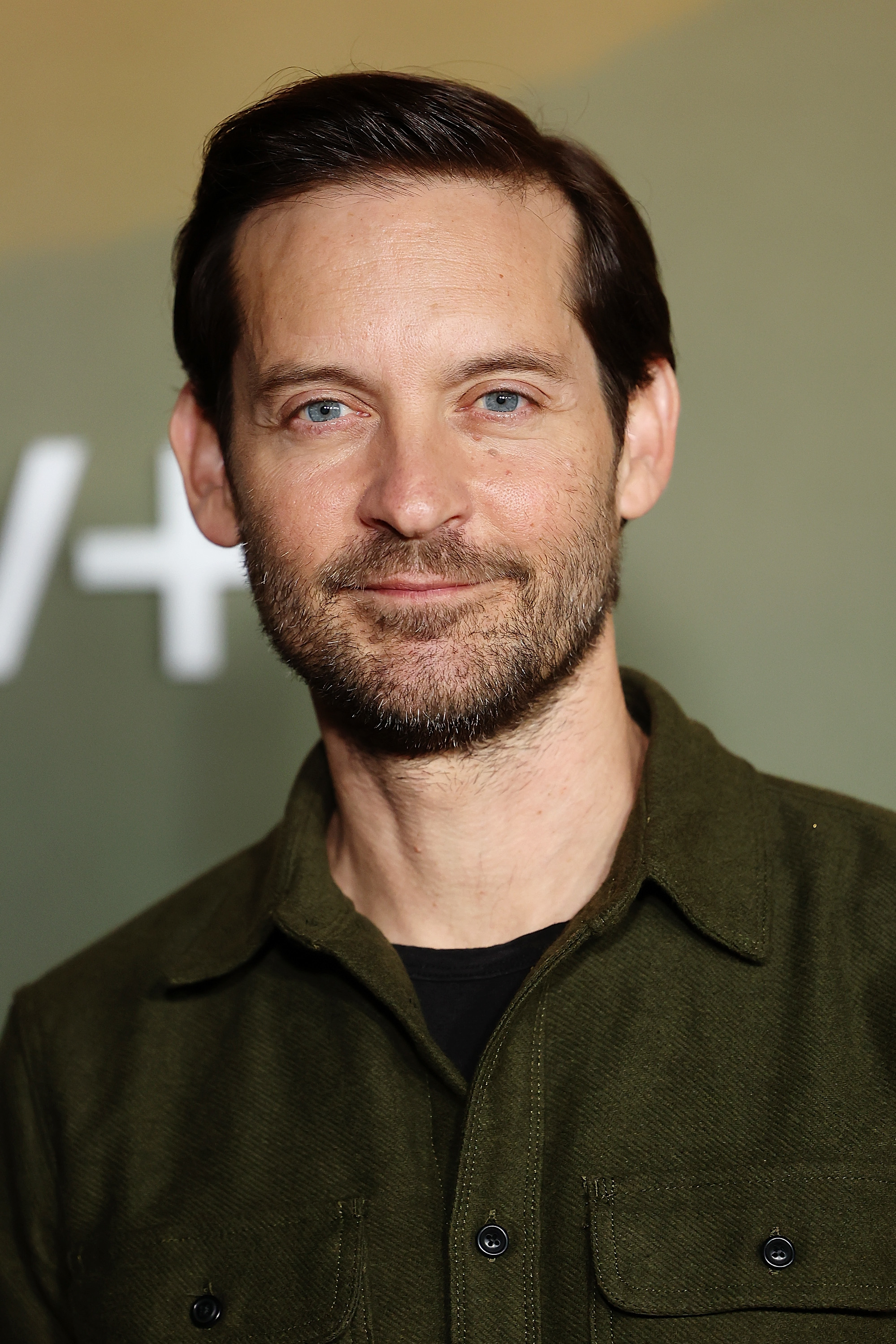 Man in a dark green shirt smiling at the camera