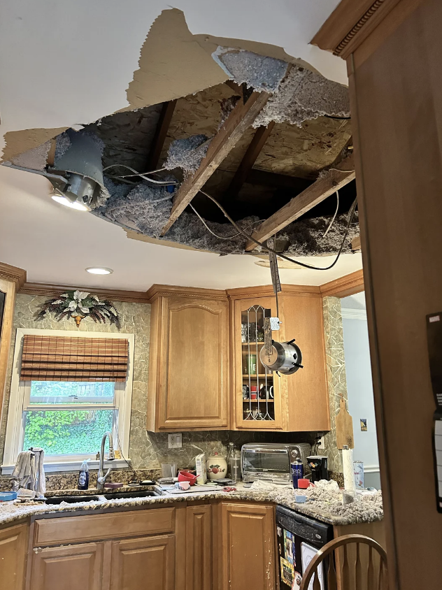 Ceiling collapse in kitchen with debris on counters and floor, exposed beams and wires visible