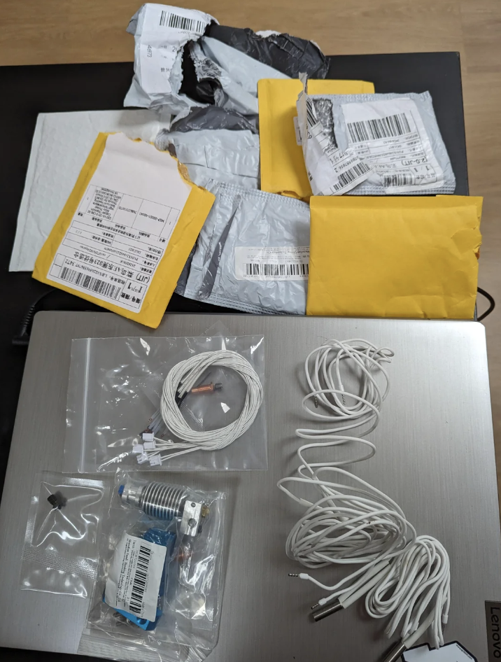 Several opened shipping packages and electronic items like cables, adapters, and connectors on a desk